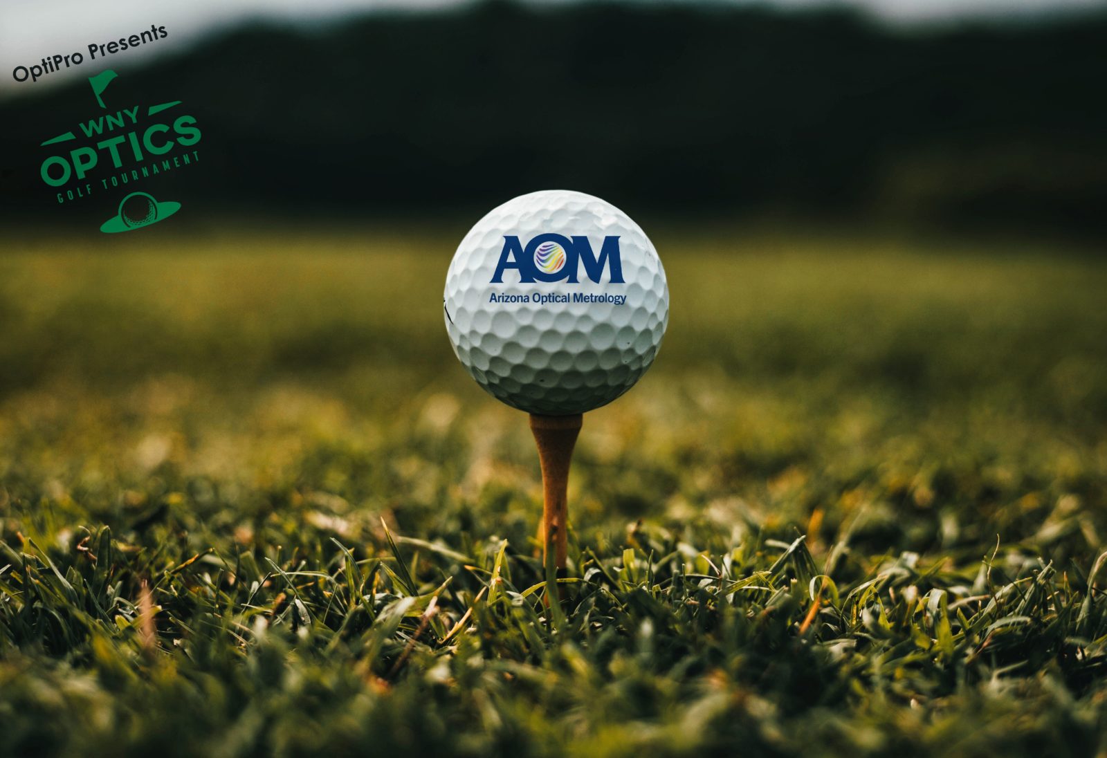 A close up of a golf ball with the AOM logo on it sitting on a tee